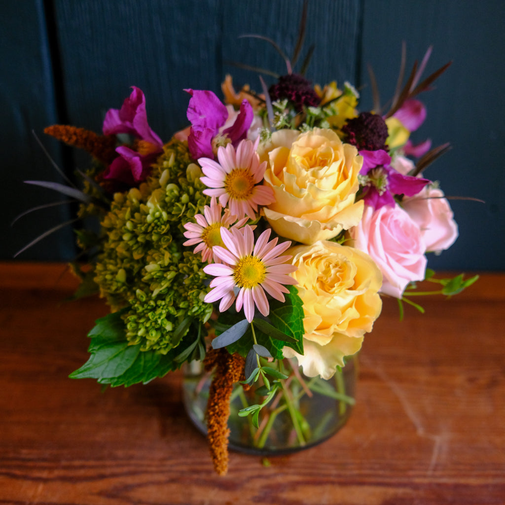 A low and compact flower arrangement in a glass vase.